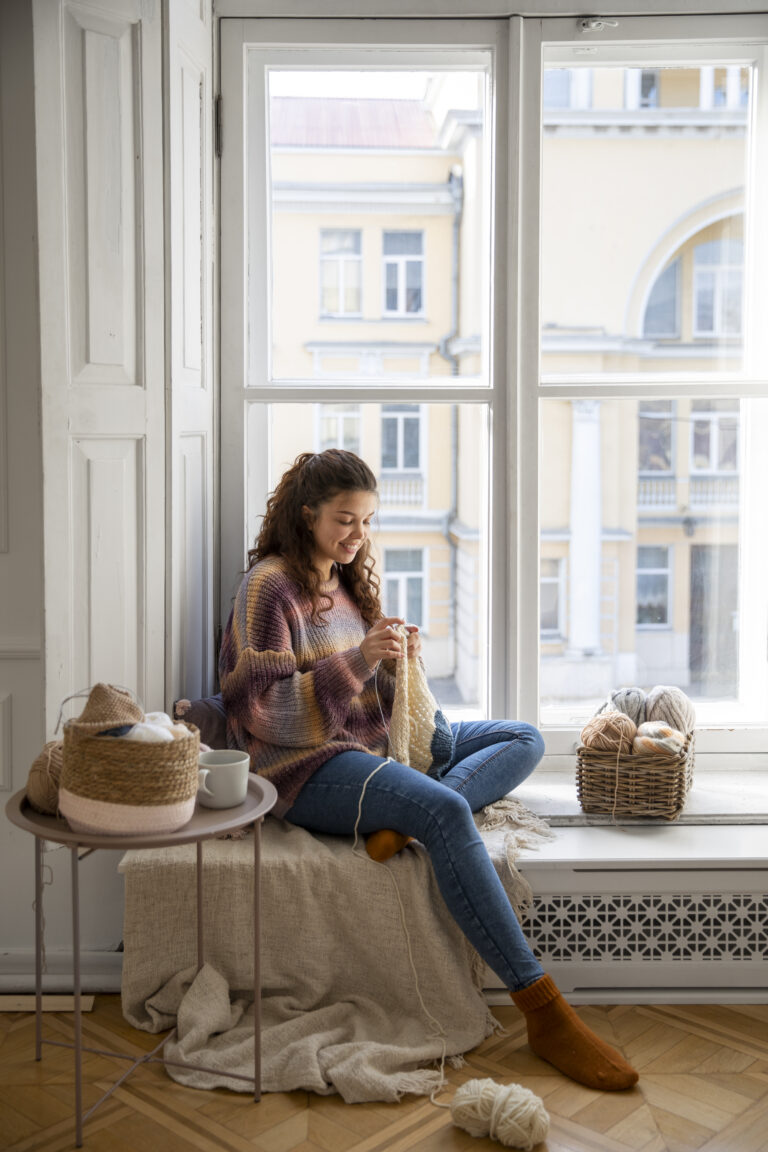 full-shot-smiley-woman-knitting-home